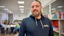 Ein Mann, der einen Pullover trägt, schaut in die Kamera