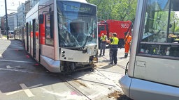 Zwei Straßenbahnen nach einen Zusammenstoß: Die Frontscheibe der Fahrzeuge ist mit Rissen durchzogen. Verkleidung am Kopf der Bahnen hängen herunter.