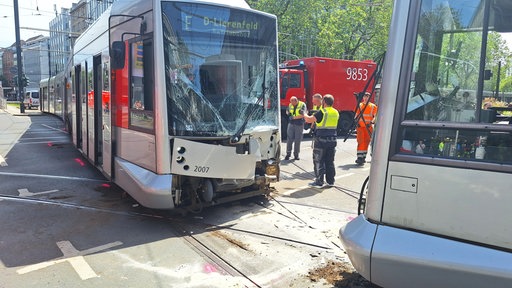 Zwei Straßenbahnen nach einen Zusammenstoß: Die Frontscheibe der Fahrzeuge ist mit Rissen durchzogen. Verkleidung am Kopf der Bahnen hängen herunter.