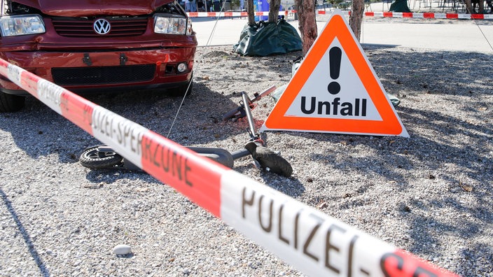 Abgesicherte Unfallstelle mit E-Scooter und Auto.