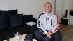 ein Mann sitzt auf dem Sofa und lächelt in die Kamera