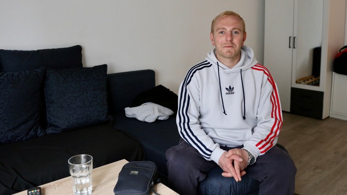 ein Mann sitzt auf dem Sofa und lächelt in die Kamera