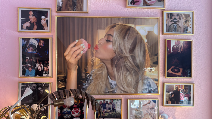 Auf dem Bild sieht man eine Wand voller Portraits von glücklichen Frauen, im Zentrum ist eine Frau, die einen pinken Muffin küsst.