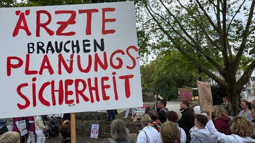 Ärzte demonstrieren in Neuss mit Plakaten.