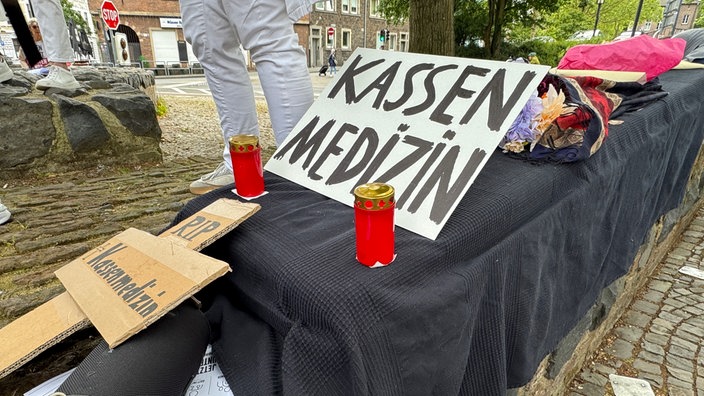Ein Sarg mit einem Plakat, auf dem "Kassenmedizin" steht.