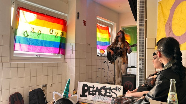 Eine Gitarrenspielerin steht auf einer Bühne