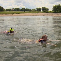 Reporterin Annika Müller und ein Strömungsretter der DLRG schwimmen im Rhein gegen die Strömung.