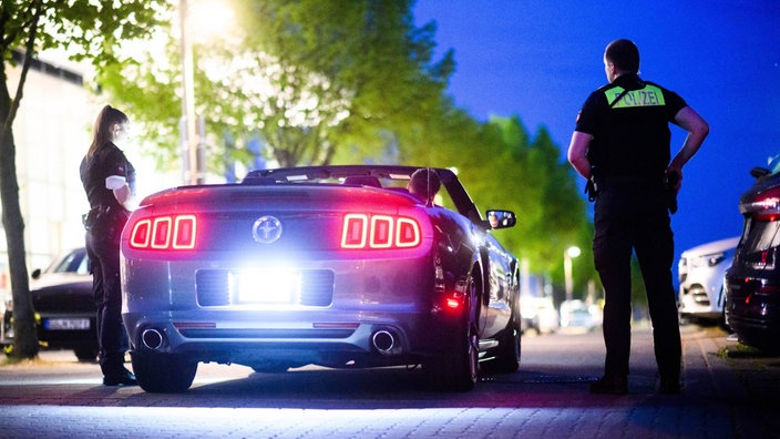 Die Polizei kontrolliert den Fahrer eines getunten Autos.