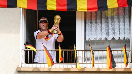 Deutschlandfan Achim Klimmeck hält ein Replika des WM-Pokals in die Höhe