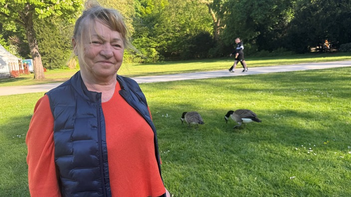 Eine Frau, Maria Chmielewska, steht im Schlosspark in Essen-Borbeck, im Hintergrund sind Kanadagänse zu sehen.
