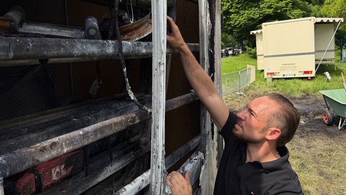 Marco Krämer betrachtet die Schäden an einem Wagen.