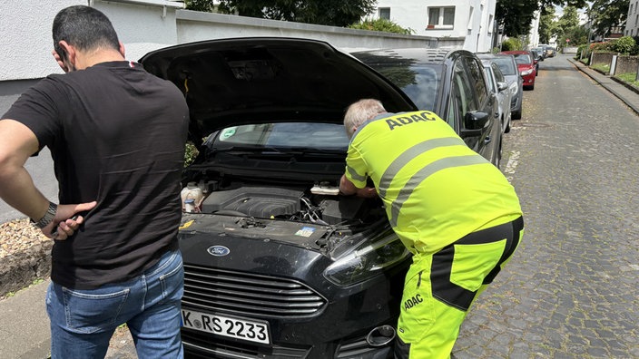 Jürgen Esser vom ADAC und ein Mann vor einem Auto mit geöffneter Motorhaube