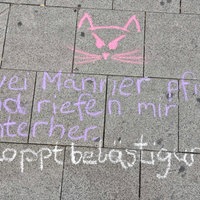 Auf Bordsteinen steht eine Kreidezeichnung zu Catcalling.