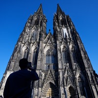 Der Kölner Dom vor blauem Himmel mit Besuchern davor.