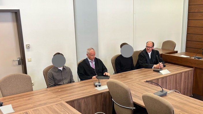 Die Angeklagten sitzen mit ihren Verteidigern im Gerichtssaal