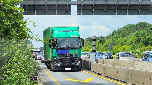 Lkw-Fahrverbot auf der A4: Ein grüner Lkw fährt auf einer vielbefahrenen Autobahn an einem Blitzer vorbei.