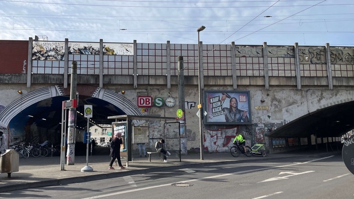 Die Bahnunterführung in Köln-Ehrenfeld, ein Mann steht an einer Bushaltestelle.