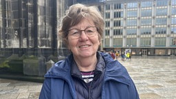 Helgard Heinrich steht in einer blauen Windjacke vor dem Kölner Dom
