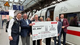 Eine Gruppe von Offiziellen steht am Bahnsteig neben einem ICE und halten ein Schild mit der neuen Verbindung nach Ostende hoch