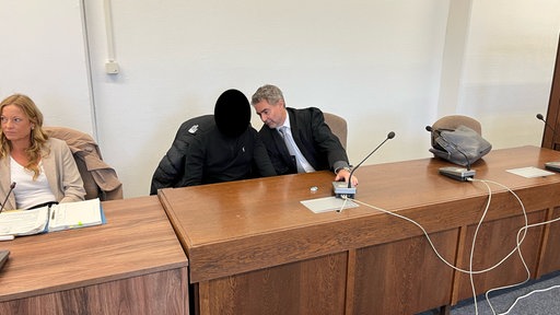 Der Angeklagte sitzt neben seinem Verteidiger im Landgericht Köln.