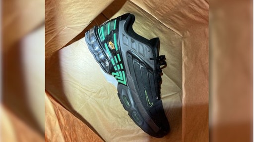 ein schwarzer Schuh der Marke Nike mit grünen Akzenten