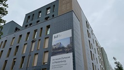 Plakat auf Hauswand kündigt das Bau-Projekt in Köln Marienburg an.
