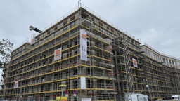 Baustelle eines Mehrfamilienwohnhauses, ringsherum ein Gerüst.