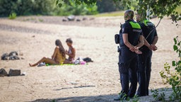  Mitarbeiter vom Ordnungsamts stehen an einem Strandabschnitt des Rheins