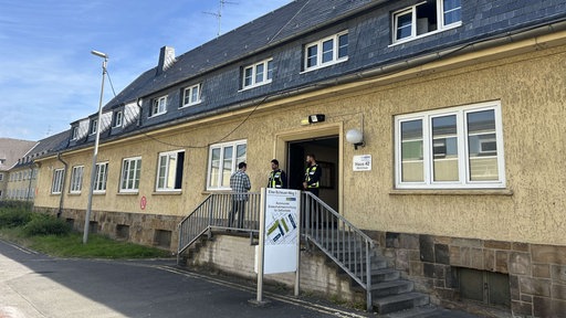 Das Gebäude in dem die berufstätigen Wohnungslosen untergebracht sind, vor der Tür zwei Sicherheitskräfte.