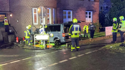 Ein Multivan ist in eine Hauswand gekracht. Polizei und Feuerwehr sichern den Unfallort. 