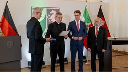 Bischof Wilmer legt seine Hand auf die Bibel und liest einen Treueeid ab.