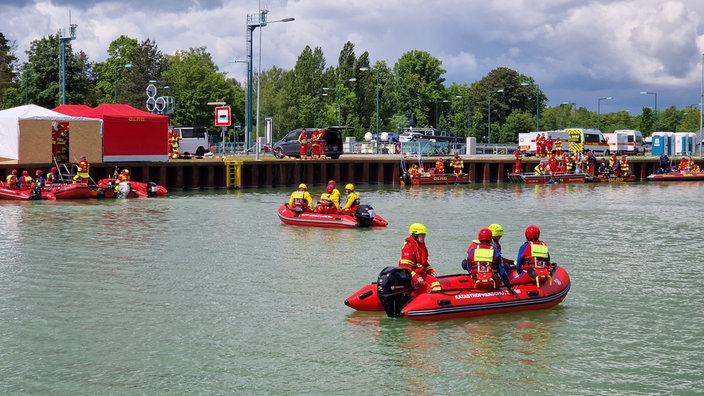 Mehrere Rettungs-Schlauchboote mit Mitgliedern des DLRG auf einem Gewässer