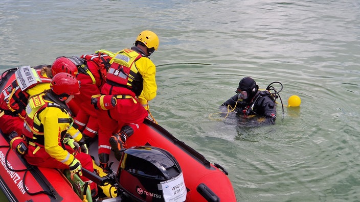ein Taucher im Wasser vor einem Rettungsboot