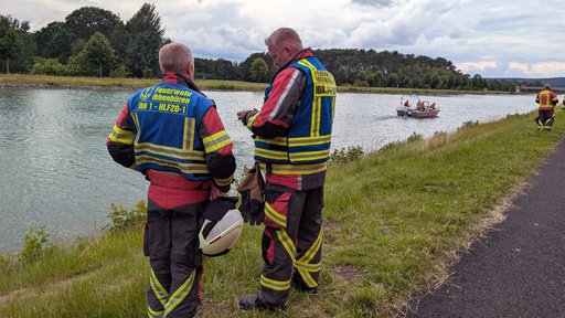 Rettungskräfte stehen am Dortmund-Emskanal bei einer großen Suchaktion. Im Hintergrund ist ein Rettungsboot mit weitere Einsatzkräften zu sehen.