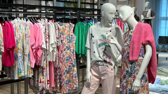 neue Sommer-Damenmode mit zwei Schaufensterpuppen im Vordergrund in einem Modehaus