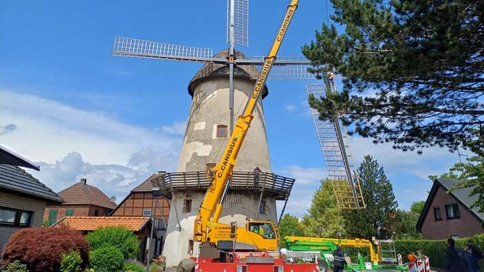 Ein Kran setzt den letzten fehlenden Flügel an die Windmühle