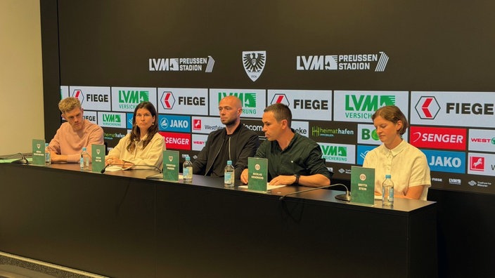 Pressekonferenz: fünf Personen sitzen an einem Tisch 
