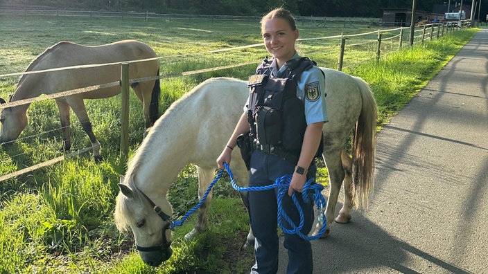 Polizistin steht neben dem entlaufenden Pony