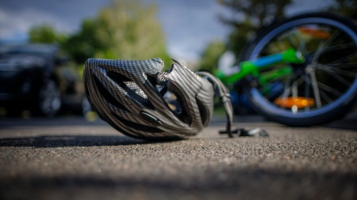 Symbolfoto: Ein Fahrradhelm liegt auf einer Straße.