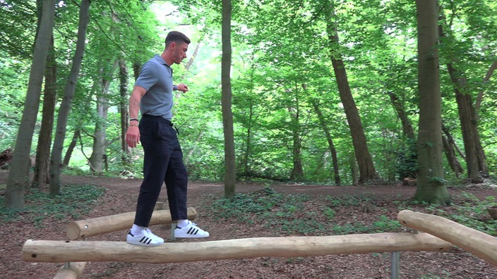 Robin Gosens balanciert auf einem Baumstamm in einem Wald.