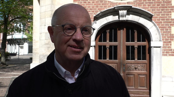 Stefan Dördelmann schaut in die Kamera und lächelt leicht. Er trägt eine Brille und einen schwarzen Pullunder.