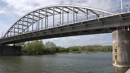 Eine Brücke über einen Fluss und im Hintergrund ein bewölkter Himmel 