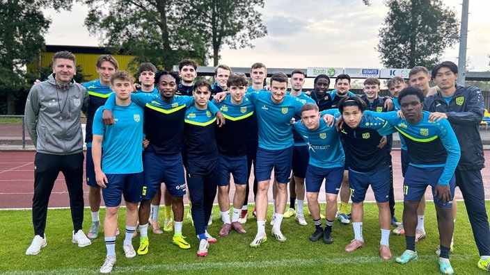 Die Fußballmannschaft vom SC St. Tönis posiert vor der Kamera. Alle tragen blaue Trikots.