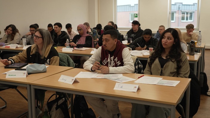 Youssef und Fati im Klassenraum einer Pflegeschule in Oberhausen, zusammenmit vielen anderen Schülern.