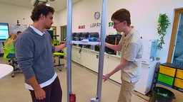 Schüler stehen in einem Klassenraum vor einem einem Gerüst, das später ein automatischer Timmer für die Fassadenbegrünung werden soll.