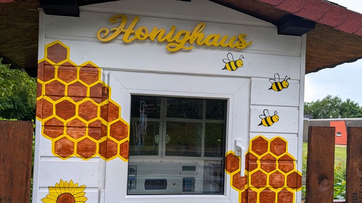 Das Honighaus in Moers, ein selbstgebauter Automat, verziert mit aufgemalten Bienen und Honigwaben.
