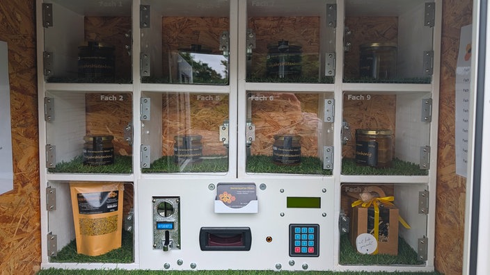 Verschiedene Honiggläser hinter Plexiglasscheiben im selbstgebauten Automaten.