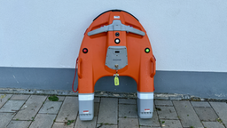 Orangefarbener Wasserrettungsroboter „Dolphin 3“ steht auf Pflastersteinen vor einer Hauswand. Sichtbar sind Tragegriffe, Signalleuchten und das Gehäuse des Rettungsgeräts.