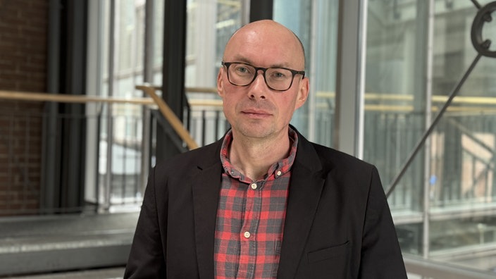 Dr. Markus Postulka, 1. Beigeordneter der Stadt Wesel. Er trägt eine schwarze Brille und ein rot-schwarz kariertes Hemd, darüber ein schwarzes Sakko.