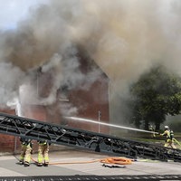 Ein Wohnaus steht im Vollbrand und Feuerwehrleute löschen den Brand